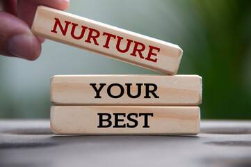 Hand holding wooden block with text - Nurture your best. Motivational concept
