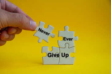 Motivational text on jigsaw puzzle with hand holding a missing jigsaw - Never ever give up.