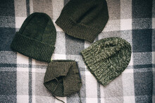 Hand-knitted Hats Of Various Shades Of Green On A Checkered Plaid