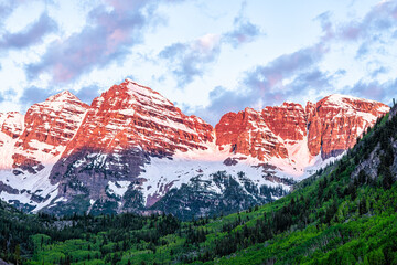 Wall Mural - Maroon Bells peak closeup with red sunrise sunlight on snowcapped rocky mountain in Aspen, Colorado with blue hour cloudy sky in June early summer dramatic view