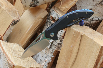 Folding knife on birch logs