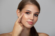 © Alena - Beautiful young woman with clean skin points her finger at her eye