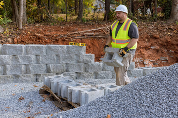 Wall Mural - Building retaining wall with retaining blocks on new property is being done by construction worker