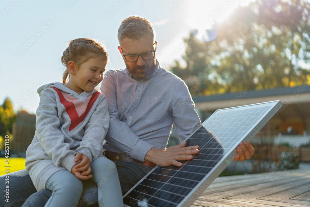 Father showing his little daughter solar photovoltaics panels, explaining how it works. Alternative energy, saving resources and sustainable lifestyle concept.