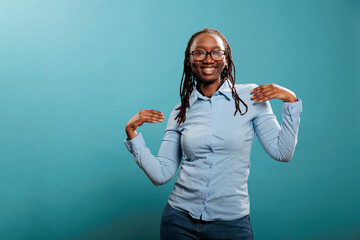 Wall Mural - Joyful happy young woman dancing with pleasure while listening to music playlist. Cheerful pleased adult person vibing through dance while celebrating an important event. Studio shot.