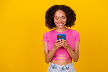Wall Mural - Photo of cheerful pretty girl hold use telephone chatting texting post comment isolated on yellow color background