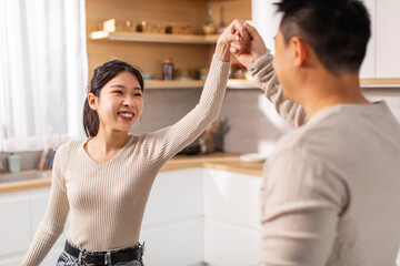 Wall Mural - Happy korean spouses dancing waltz at kitchen