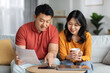 © Prostock-studio - Happy asian family calculating monthly spending at home