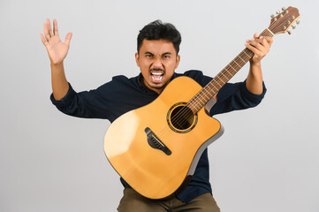 Wall Mural - Portrait of Young Asian man playing an acoustic guitar isolated on white background