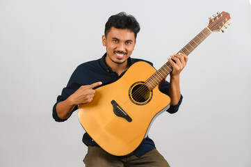 Wall Mural - Portrait of Young Asian man playing an acoustic guitar isolated on white background