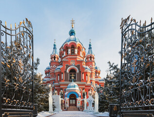 Winter Irkutsk. Cathedral of Kazan Icon of Mother of God during Christmas holidays. View of churchyard with ice sculptures of Saints from entrance with wrought iron gates. Translation: Merry Christmas