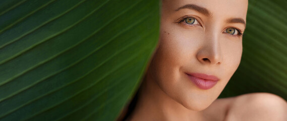 green beauty portrait. organic cosmetic concept. beautiful young woman posing against and behind fre