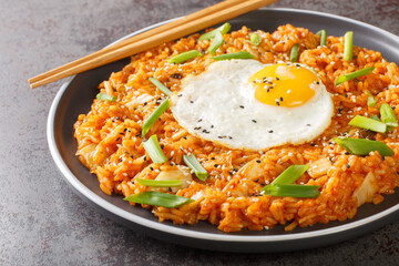 Wall Mural - Homemade kimchi fried rice topped with fried egg closeup on the plate on the table. Horizontal