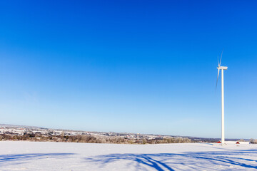 Poster - Wind turbine on a snowy field with a beautiful view