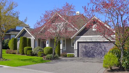 Wall Mural - Establishing shot of two story stucco luxury house with garage door, big tree and nice spring blossom landscape in Vancouver, Canada, North America. Day time on May 2022. ProRes 422 HQ.