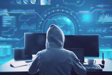 Poster - hacker in hoodie sitting at desktop with coffee cup and using computer monitors with abstract glowing digital business interface with globe and various other icons on blurry blue background. 