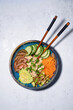 Poke bowl on white background. Poke with chicken and fresh vegetables. Traditional Hawaiian food on blue salad plate on the table. Sushi restaurant menu. Healthy diet. Popular food concept. Copy space