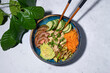 Poke bowl on white background. Poke with chicken and fresh vegetables. Traditional Hawaiian food on blue salad plate on the table. Sushi restaurant menu. Healthy diet. Popular food. Green lemon leaves