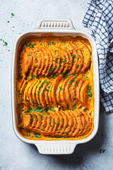 Wall Mural - Roasted sweet potato gratin with parsley in ceramic pan. Vegan healthy recipe concept.