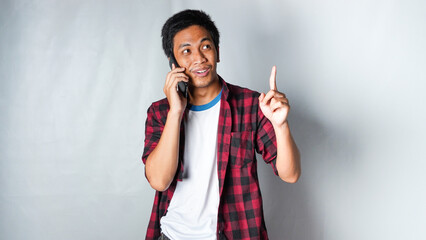 asian adult man wearing red flannel calling someone and get idea with smiling face isolated white background