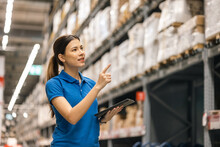 Young Female Worker In Blue Uniform Checklist Manage Parcel Box Product In Warehouse. Asian Woman Employee Holding Tablet Working At Store Industry. Logistic Import Export Concept.