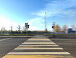 Pedestrian crossing to the embankment. A road zebra with white and yellow stripes leads across the road to the river embankment. Cars rush along the road, leaving a blurry trail.