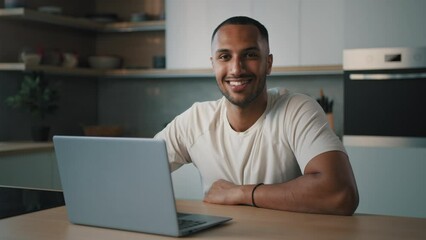 Smiling African millennial man guy American male user freelancer at home kitchen finish distant work with laptop satisfied with computer app online website networking shopping looking at camera smile