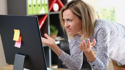 Upset woman looking at laptop screen with angry expression