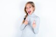 beautiful caucasian teen girl wearing gray turtleneck sweater over white wall directs fingers at camera selects someone. I recommend you. Best choice