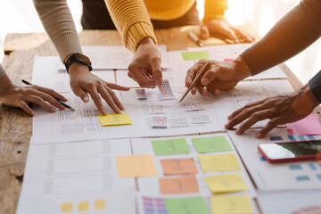a ux design team is a confluence of user research, ux, ui design with layout paper on desk.