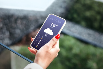 rainy weather forecast. female hand holds a mobile phone and looks at the weather forecast for the d
