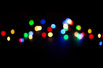 Wall Mural - multicolored defocused lights in the middle of a black background