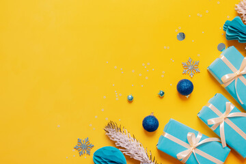Wall Mural - Merry Christmas background with snowflakes, gifts and festive decorations top view on colored background