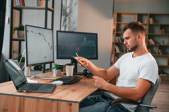 Laptop is on the table. Young stock broker is working in the office by using computer