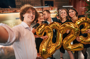 Wall Mural - 2023 is coming. With balloons. Group of people in beautiful elegant clothes are celebrating New Year indoors together