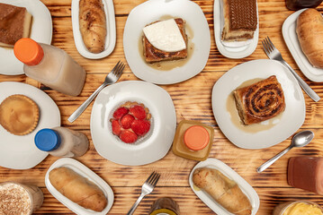 Typical Venezuelan and Latin desserts, golfeados, creams, quesillos, stuffed pieces and strawberry tartlet on a charred pine wood table