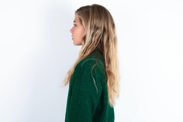 Wall Mural - Profile portrait of nice beautiful caucasian teen girl wearing green knitted sweater over white wall look empty space toothy smile