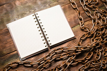Wall Mural - open blank page notebook with copy space and old rusty iron chain on the wooden table background. to