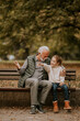 © BGStock72 - Grandfather spending time with his granddaughter on bench in park on autumn day