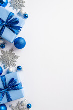 Christmas Concept. Top View Vertical Photo Of Gift Boxes With Ribbon Bows Blue White Silver Baubles And Glitter Snowflake Ornaments On Isolated White Background With Copyspace