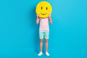 Full body photo of attractive young guy smile emoji pinata hide face dressed stylish pink garment isolated on aquamarine color background