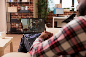 Poster - Office worker attending online videocall meeting, using laptop and webcam while he works remotely from home. Talking to person on remote videoconference chat, teleconference call.