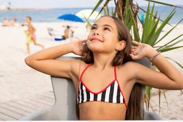 Little girl sitting in a tropical cafe. Outdoors