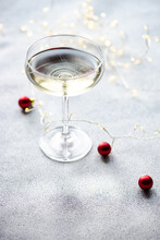 Close-Up Of A Glass Of Champagne Wine Decorated With String Lights And Christmas Baubles