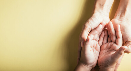 Wall Mural - Close up hands children on adult mother hand, Top view person kid stack mom palms, Parents and little kid holding empty hands together isolated on yellow background, Family day care concept