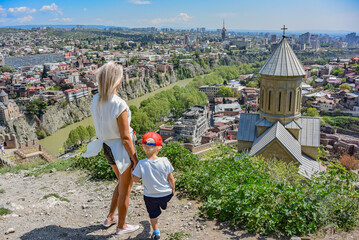 Tbilisi, Georgia-April 28, 2019: a young girl with a child on the background of a beautiful bird's-eye view of the Central part of Tbilisi and the Church of St. Nicholas the Wonderworker.