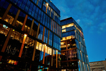 Wall Mural - Office building facade with illuminated windows at night city. Warsaw city downtown district with skyscraper facade. Night city panorama