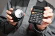 Calculation of the cost of installation of a video surveillance system concept. Video surveillance service worker holds a cctv security camera and calculator close up.