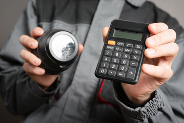 Wall Mural - Calculation of the cost of installation of a video surveillance system concept. Video surveillance service worker holds a cctv security camera and calculator close up.