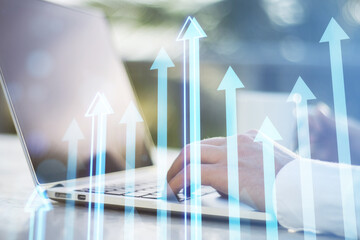 Fototapete - hands at office workplace with coffee cup using laptop with creative growing arrows chart on blurry city background. Return on investment, finance and market growth concept. Double exposure.
